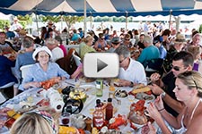 Photo of kettlebake guests eating clams, lobsters, chicken, sweet potatoes, and corn under the tent